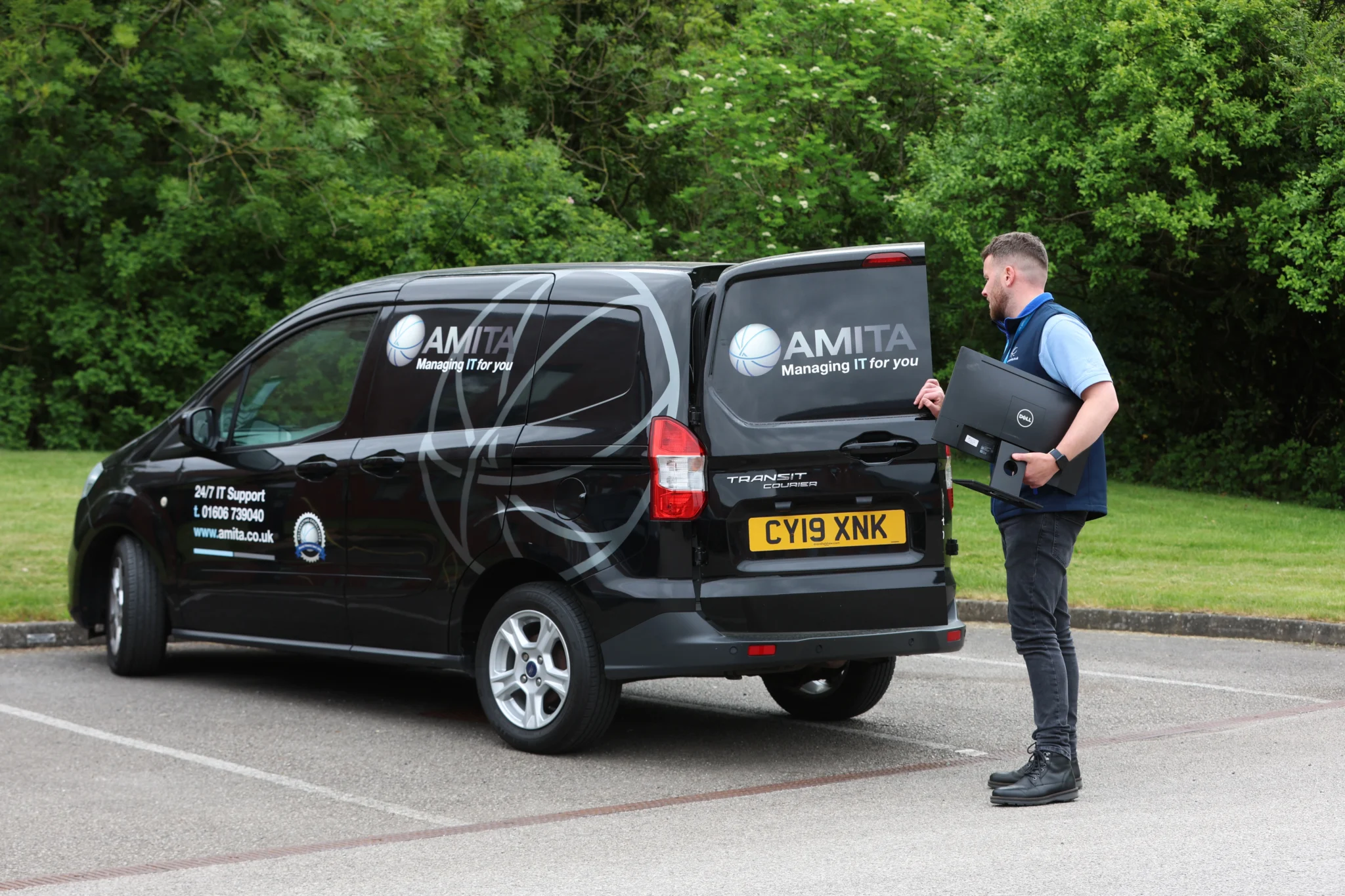 a man opening the amita van and holding a monitor